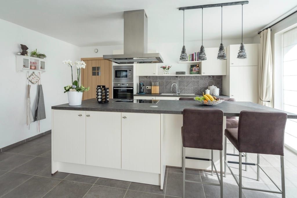 White kitchen with an island, pendant lights and a range hood